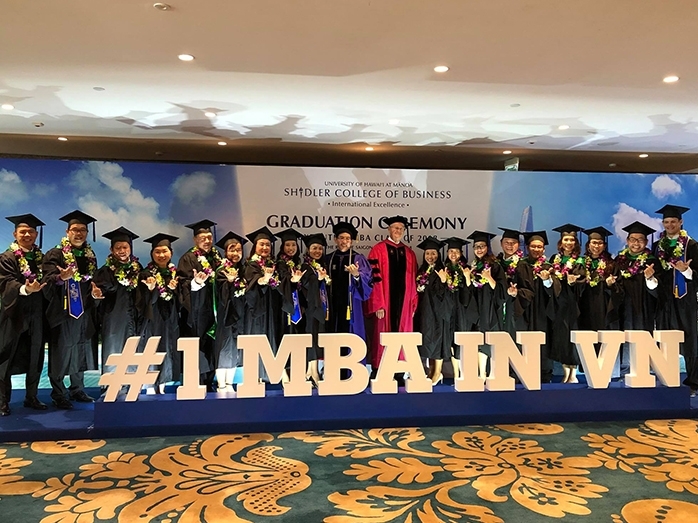 Shidler Professor and VEMBA Director Tung Bui and Shidler Dean Vance Roley (center) celebrate with the VEMBA class at a commencement ceremony in Ho Chi Minh City. 